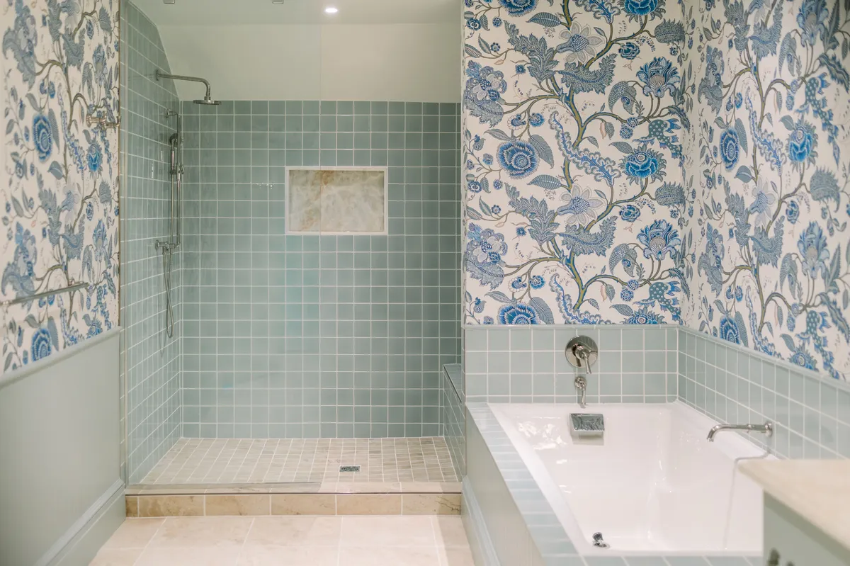 A serene bathroom adorned with floral wallpaper, featuring both a spacious shower area and a relaxing bathtub. The space exudes calm and invites guests to indulge in self-care and relaxation, perfect for soothing muscles after active days.